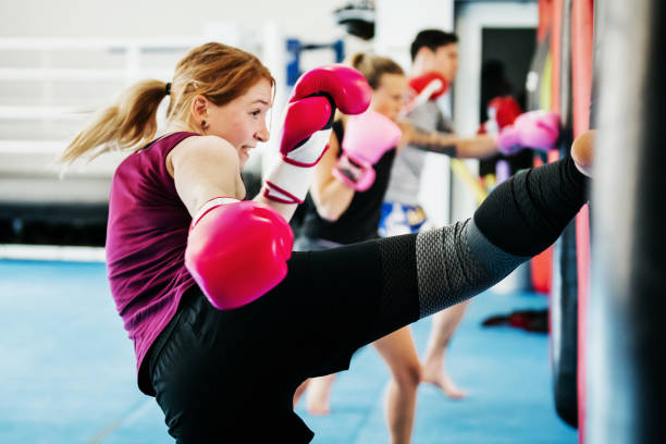 Women practicing non-contact kickboxing with heavy bags in a gym